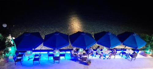 a group of people sitting under blue umbrellas at San Georgio Hotel in Tsoútsouros