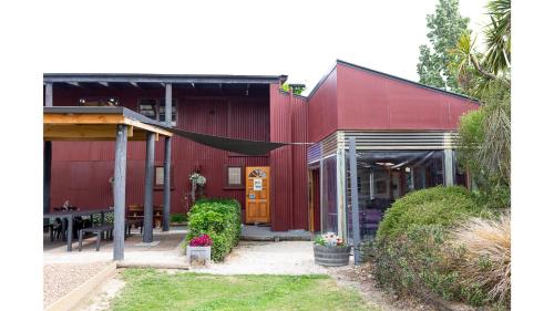 a red building with a patio and a table at Pacific View by Tiny Away in Leithfield