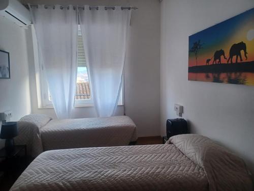 two beds in a hotel room with a window at Dormen in Guspini