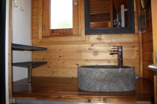 a bathroom with a stone sink in a wooden wall at Volcans Vacances Les Chalets Du Lac in Aydat