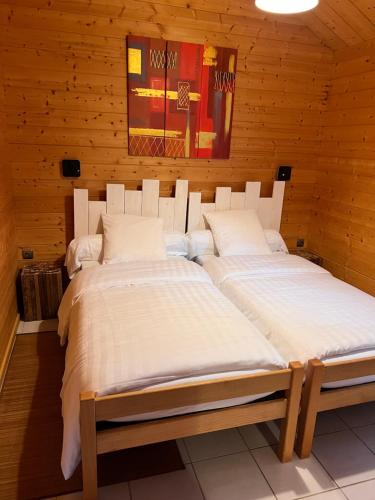 two beds in a room with wooden walls at Volcans Vacances Les Chalets Du Lac in Aydat