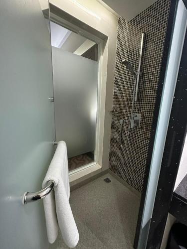 a bathroom with a shower and a towel on a rack at Ming Garden Hotel & Residences in Kota Kinabalu