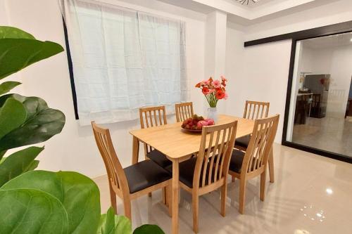 a dining room table with chairs and a vase of flowers at Breezy Bliss Home in Chiang Mai