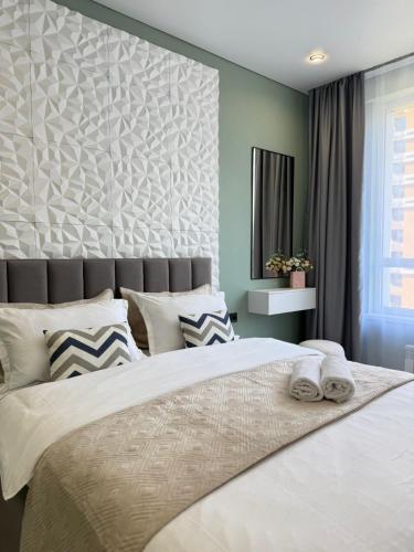 a bedroom with a large bed with two towels on it at Двухкомнатная квартира с дизайнерским интерьером и видом на горы in Almaty