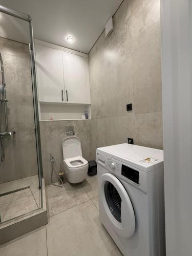 a bathroom with a washing machine and a toilet at Двухкомнатная квартира с дизайнерским интерьером и видом на горы in Almaty