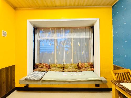 a window seat in a room with a yellow wall at Bohol Seafront Villa Pasan Cove a resort homestay in Guindulman