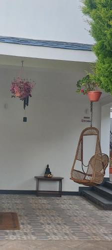 a living room with a rattan chair and a table at Magizham Homestay in Kodaikānāl