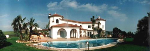 une grande maison blanche avec une piscine en face de celle-ci dans l'établissement Villa Habana, à Fonte Nuova