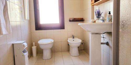 a bathroom with a sink and a toilet and a window at Vittoria in Tortolì