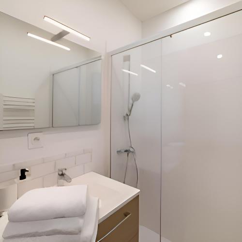 une salle de bain blanche avec une douche et un lavabo dans l'établissement L’élégant, charmant studio hyper centre Gare 800m, à Agen