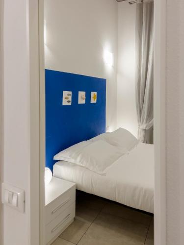 a bedroom with a bed with a blue wall at Alla Casa Rosa al Mare, Central Seafront Stay, Air Conditioning, Wi-Fi, the Ideal Choice for a Relaxing and Exciting Coastal Escape, with available on request at 20,00 euro per night Private Garage, Welcome kit Priority, Prosecco and Canestrelli in Rapallo