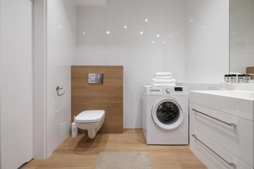 a white bathroom with a washing machine and a sink at Symphony Baltica Towers Apartamenty in Gdańsk