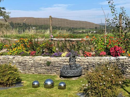 a garden with a stone wall and a statue in the grass at Laburnum B&B in Kenmare