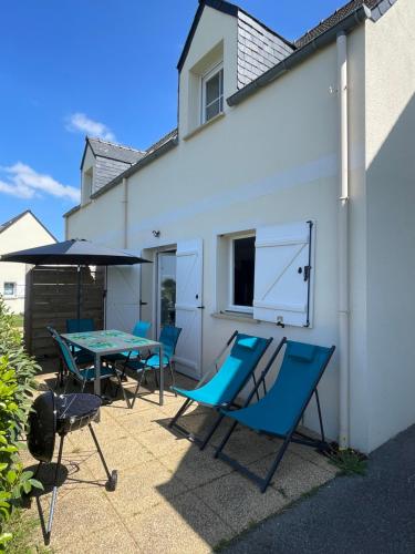 patio con sedie blu, tavolo e ombrellone di Les terrasses de Pentrez - 11 a Saint-Nic