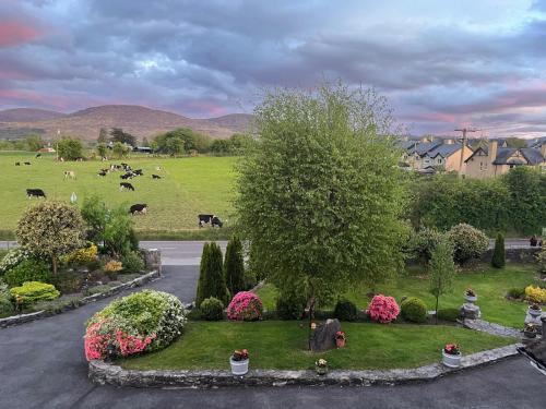 a park with cows in a field with a tree and flowers at Laburnum B&B in Kenmare