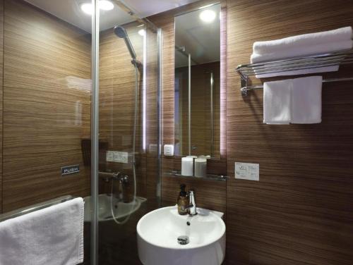 a bathroom with a sink and a glass shower at Hotel Glad One Kyoto Shichijo by M's in Kyoto