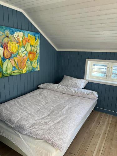 a bed in a room with a painting on the wall at Landlig og Idyllisk in Sylling