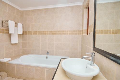 a bathroom with a tub and a toilet and a sink at Tamboti Guest Lodge in Pretoria
