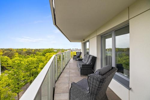 a balcony with chairs and a view of trees at Symphony Baltica Towers Apartamenty in Gdańsk