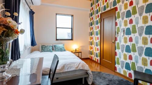 a bedroom with a bed and a table and a window at KAMON relaxing, Japanese spacious room in Osaka