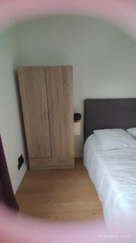 une chambre avec un lit et une armoire en bois dans l'établissement Studio Smarty, à Parigné-lʼÉvêque