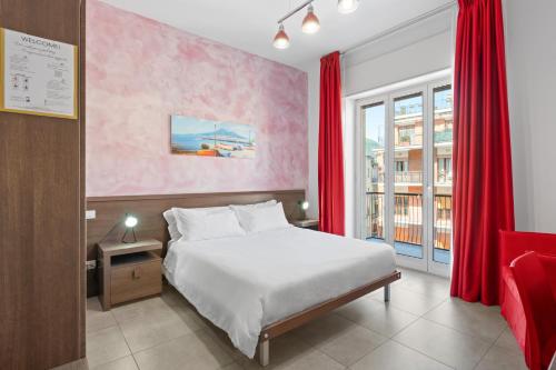 a bedroom with a white bed and red curtains at Giufrania Rooms in Castellammare di Stabia