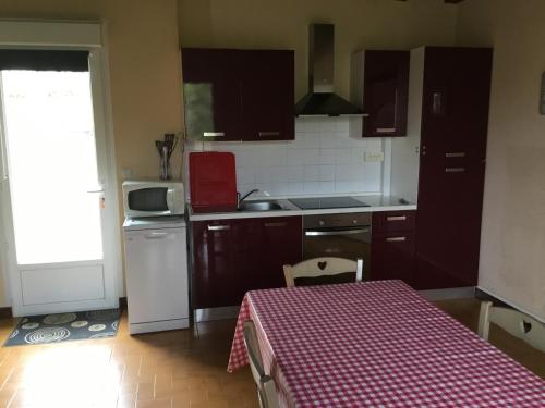 a kitchen with brown cabinets and a table with a red checkered table cloth at La maison du bonheur in Milhac