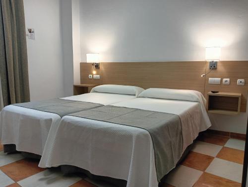 a large white bed in a room with two lights at Don Paula in Córdoba