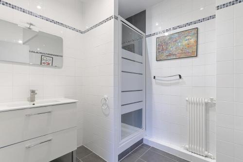 une salle de bain blanche avec une douche et un lavabo dans l'établissement Beaugrenelle Tour Eiffel I Cosy Apartment 4P, à Paris