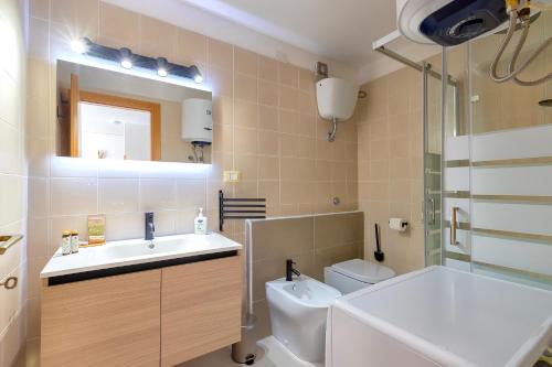 un bagno con lavandino, WC e specchio di Sea Pine Retreat A Sorso a Sorso