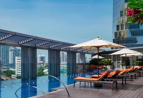 a pool with chairs and umbrellas on a building at Bangkok Marriott Hotel Sukhumvit in Bangkok