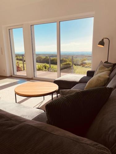 a living room with couches and a table and large windows at Ferienhaus Auszeit in Laubach