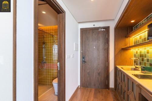 a bathroom with a toilet and a wooden door at Mandala Oceanfront Driftwood Resort in Phan Thiet