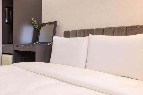 a bed with white pillows and a desk with a mirror at Giverny Hotel in Gyeongju