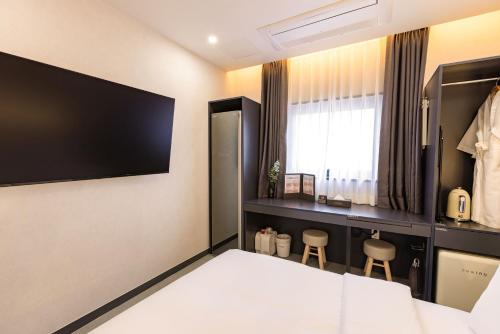 a bedroom with a bed and a tv on the wall at Giverny Hotel in Gyeongju