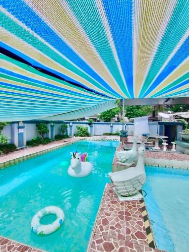 ボゴールにあるVila Princess,Sentul 4bedroom dan Tenda Camping,Private pool, Tenis meja, mini billiard, Karaoke, Ayunan,BBQ, 08satu3 80satu6 4satu5satuの大きな傘と椅子のあるプール