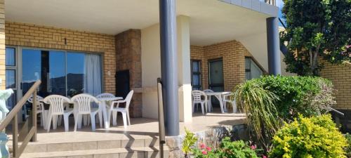 a balcony with white chairs and tables on a building at Kleinmond Panorama Holidays in Kleinmond