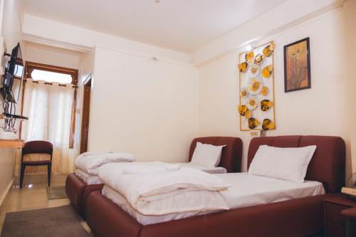 two beds in a room with white sheets at Hotel Dilli-Phu in Bomdila