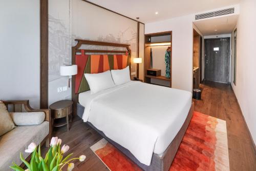a bedroom with a large white bed and a couch at Mandala Oceanfront Driftwood Resort in Phan Thiet