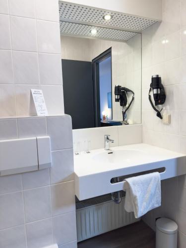 a bathroom with a sink and a mirror at Coffee Fellows Hotel Frankfurt Airport-Langen in Langen