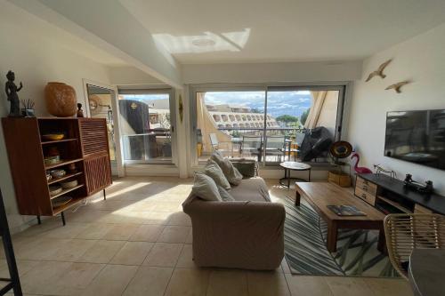 un salon avec un canapé et une télévision dans l'établissement Le Port Camargue - 2 bedrooms air conditioning terrace and swimming pool!, au Grau-du-Roi