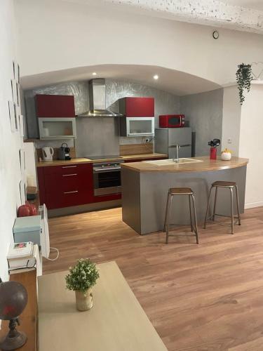 une grande cuisine avec des placards rouges et un grand îlot dans l'établissement Le Montpelliérain - Studio dans l’écusson !, à Montpellier