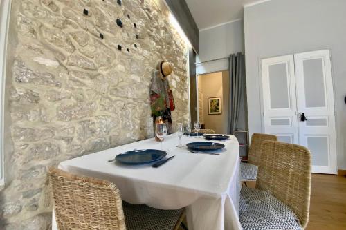 une table blanche avec des chaises et un mur en pierre dans l'établissement Le Coeur de Ville - Charmant pour 2 personnes !, à Montpellier