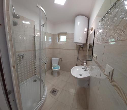 a bathroom with a toilet and a shower and a sink at Mórocz Vendégház in Balatonboglár