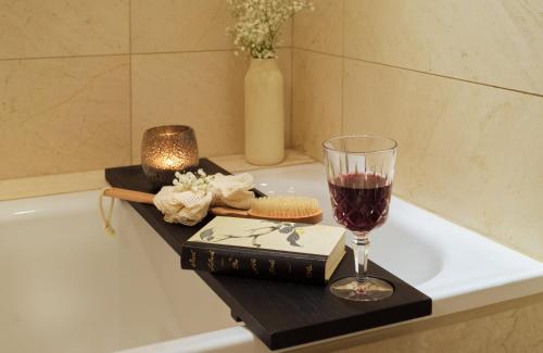 a glass of wine and a book sitting on a bath tub at Hotel Alden Splügenschloss Zürich - Leonardo Limited Edition in Zürich