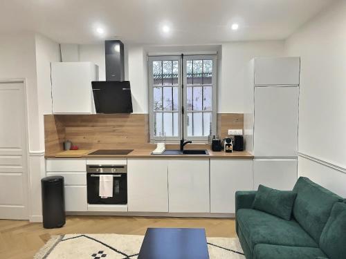 une cuisine avec des placards blancs et un canapé vert dans l'établissement Château Versailles, logement Neuf, à Versailles