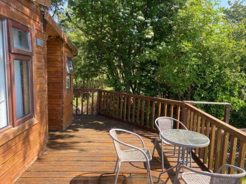 a wooden deck with two chairs and a table at Lakeside Lodge - Castlemartyr - Sleeps 4 in Castlemartyr