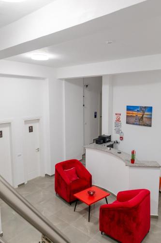 a living room with two red chairs and a table at Vullkan Hotel in Ksamil