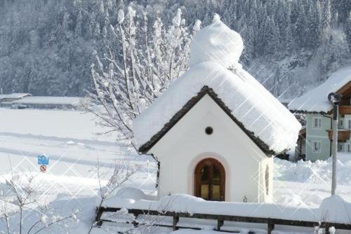 a snow covered roof of a house with a fence at Haus Sonne in Kirchdorf in Tirol