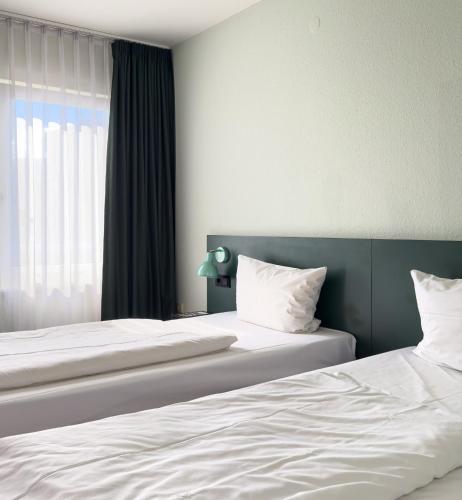 two beds in a bedroom with a window at Coffee Fellows Hotel Frankfurt Airport-Langen in Langen